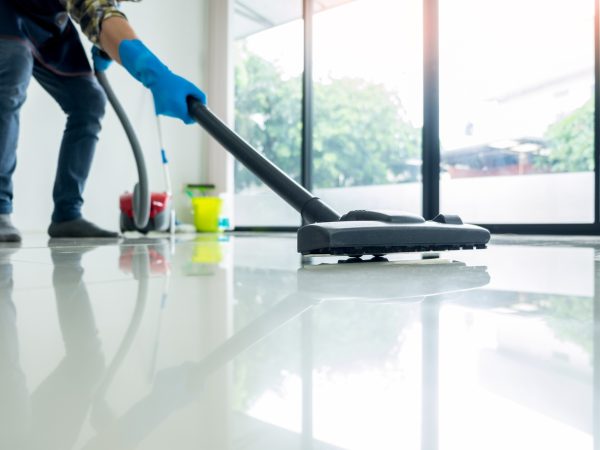 Young attractive man is cleaning vacuum commercial cleaning equipment on floor at home helping wife